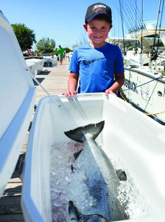 Andrews Mathews, 7, poses with his 26.8 pound king salmon, the heaviest catch of the day, during the 2018 Tri-Cities Kiwanis Salmon Tournament on Lake Michigan in Grand Haven, Mich., on Thursday, July 26, 2018. (Casey Sykes for Kiwanis Magazine)